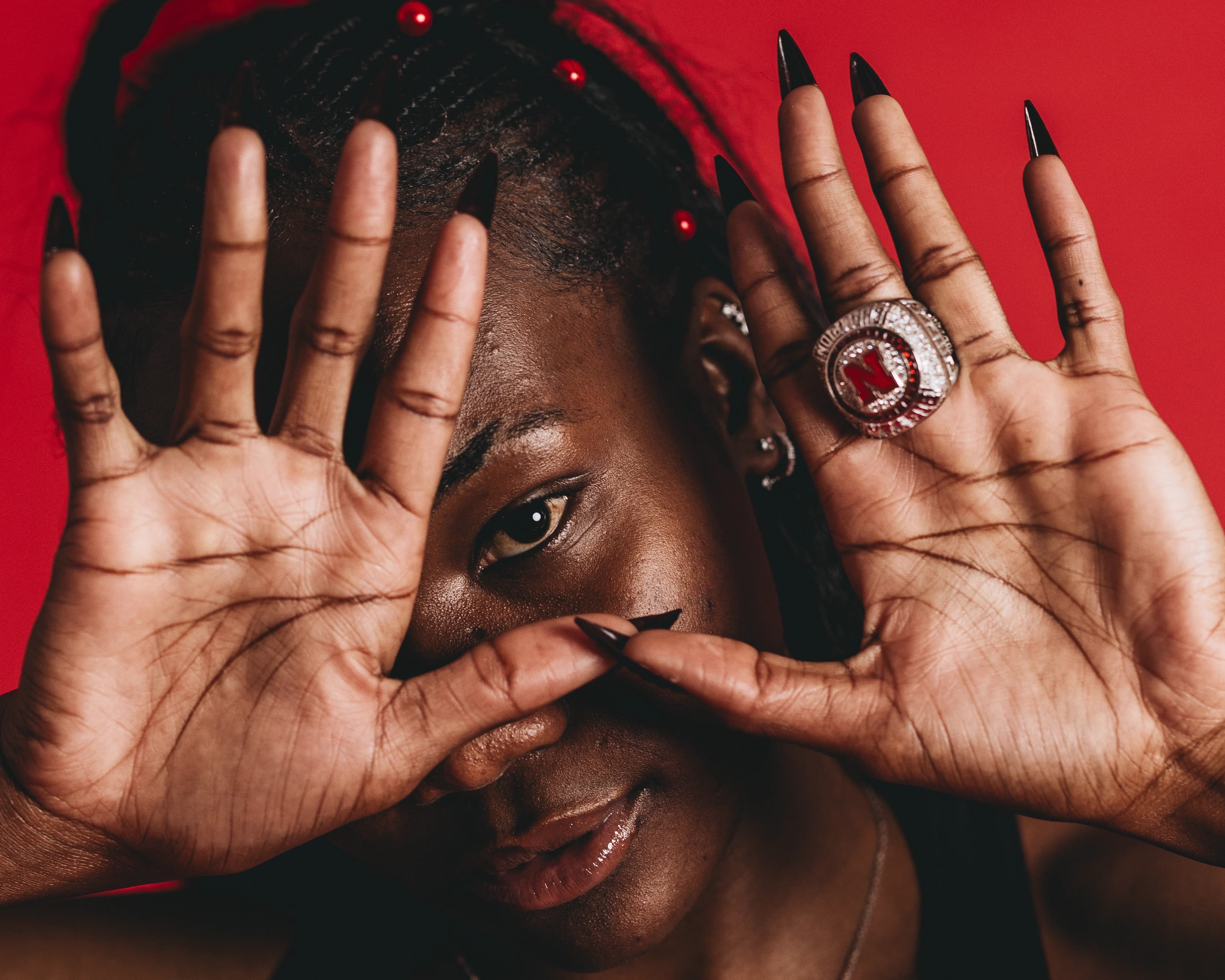University of Nebraska track and field athlete Rhianna Phipps peers through her raised hands to display her Big Ten championship ring during a 2025 media day portrait session in Lincoln, Neb. Phipps, a five-time USTFCCCA All-American, won the Big Ten outdoor triple jump title in 2024 with a personal-best mark of 43 feet, 11 3/4 inches.